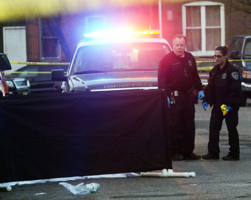 Trenton police investigate a murder in the 100 block of Hudson Street Wednesday afternoon. The victim is on the ground behind the black curtain. (Gregg Slaboda - Trentonian)
